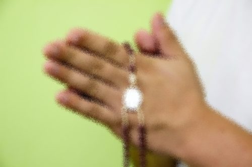 manos con un rosario