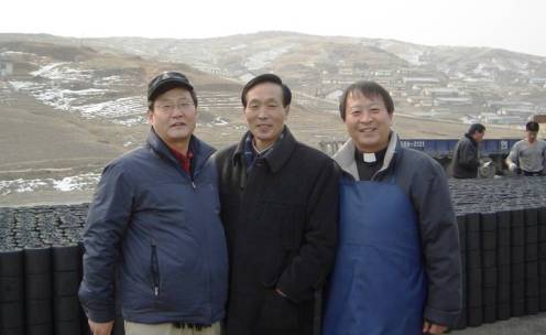 North Korea 2007 Father Lee Eun-hyung (right) near the North Korean town of Kaesong in front of unloaded coal briquettes in 2007. Also in the picture are a co-organiser of the relief supply from South Korea (left) and a senior government official from North Korea (centre).