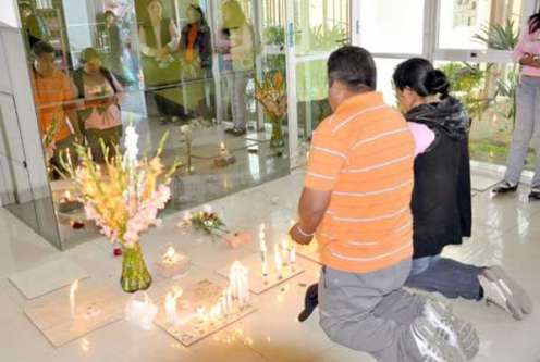 pareja rezando frente a imagen de guadalupe en un vidrio