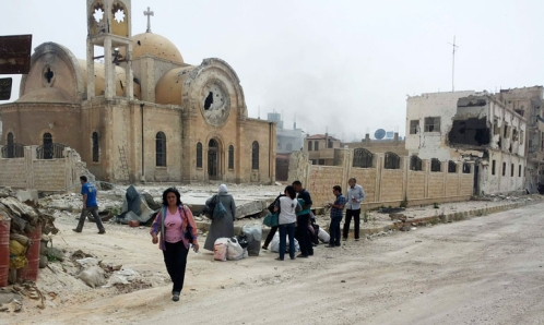 residentes caminan cerca de una iglesia bombardeada el 8 de junio en Qusair