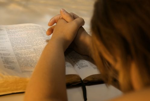mujer orando sobre biblia