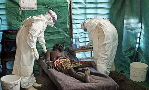 paciente con signos de ebola en cama con medicos visitandolo