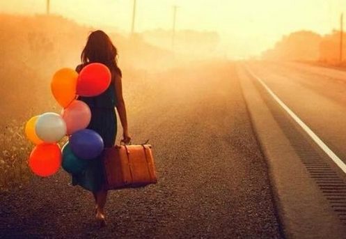 mujer camina con globos y maleta