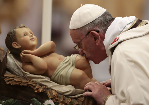 Pope Francis kisses the baby Jesus statue as he leads the Christmas night mass in the Saint Peter's Basilica at the Vatican