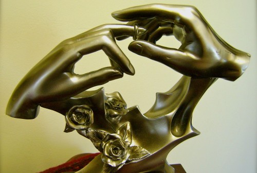 escultura de manos poniendose un anillo fondo