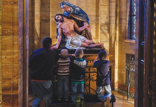 padre e hijos mirando estatua de descendimiento