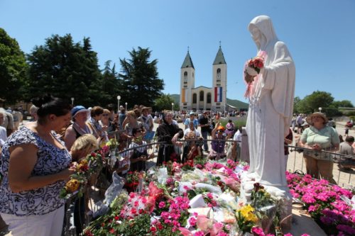 peregrinos llevan flores a estatua de medjugorje
